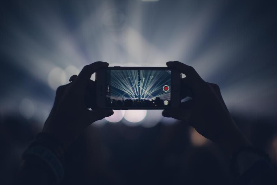 Mãos segurando um celular na horizontal enquanto gravam um vídeo