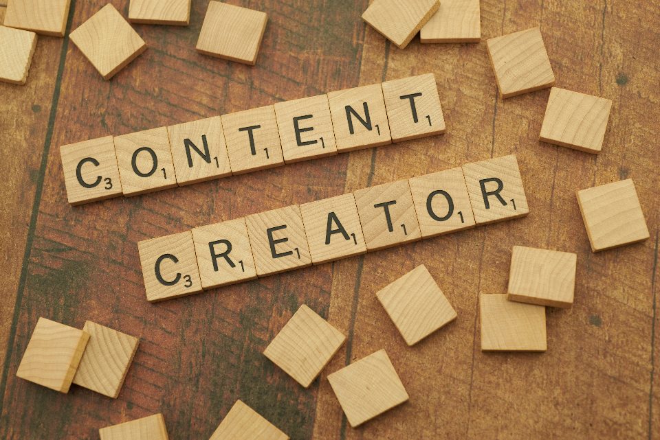 Peças de um jogo de palavras formando “content creator” sobre uma mesa de madeira