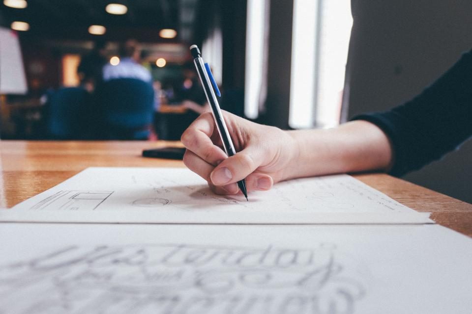 Mão desenhando um esboço a lápis sobre o papel