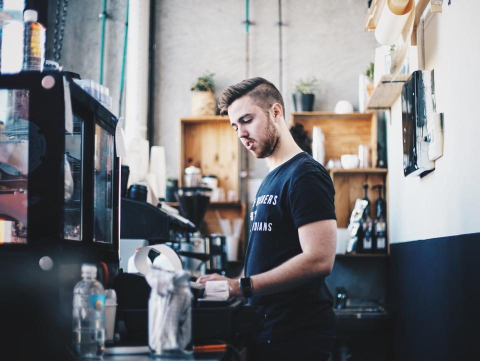 Homem trabalhando atrás do balcão de uma pequena loja de café
