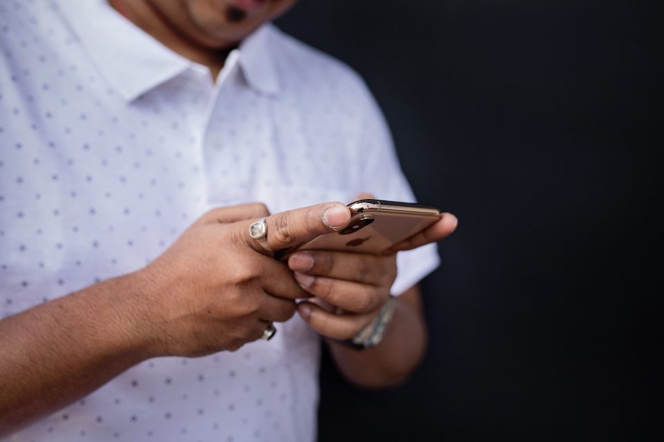 Homem de camisa branca digitando uma mensagem no celular