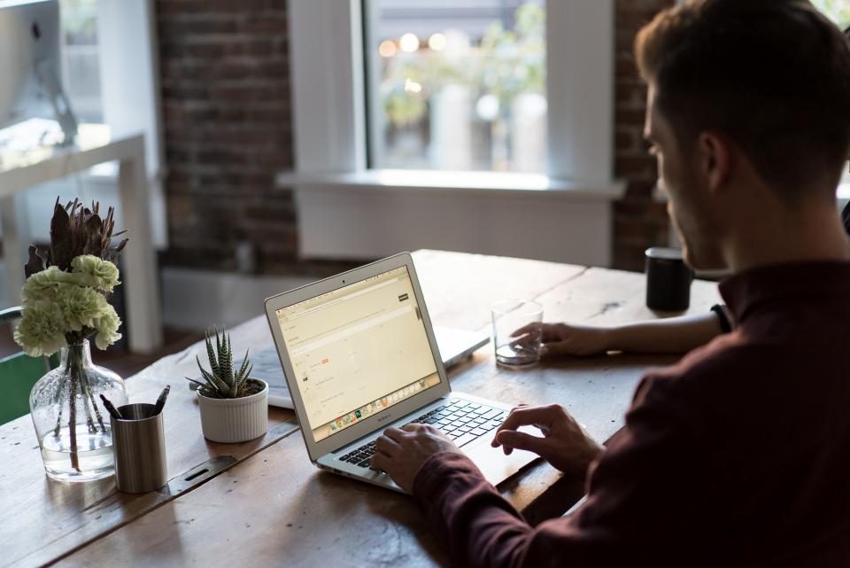 Homem trabalhando no notebook em uma mesa de escritório iluminada