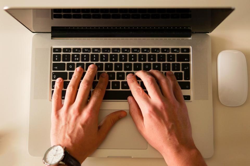Mãos digitando no teclado de um notebook, vistas de cima