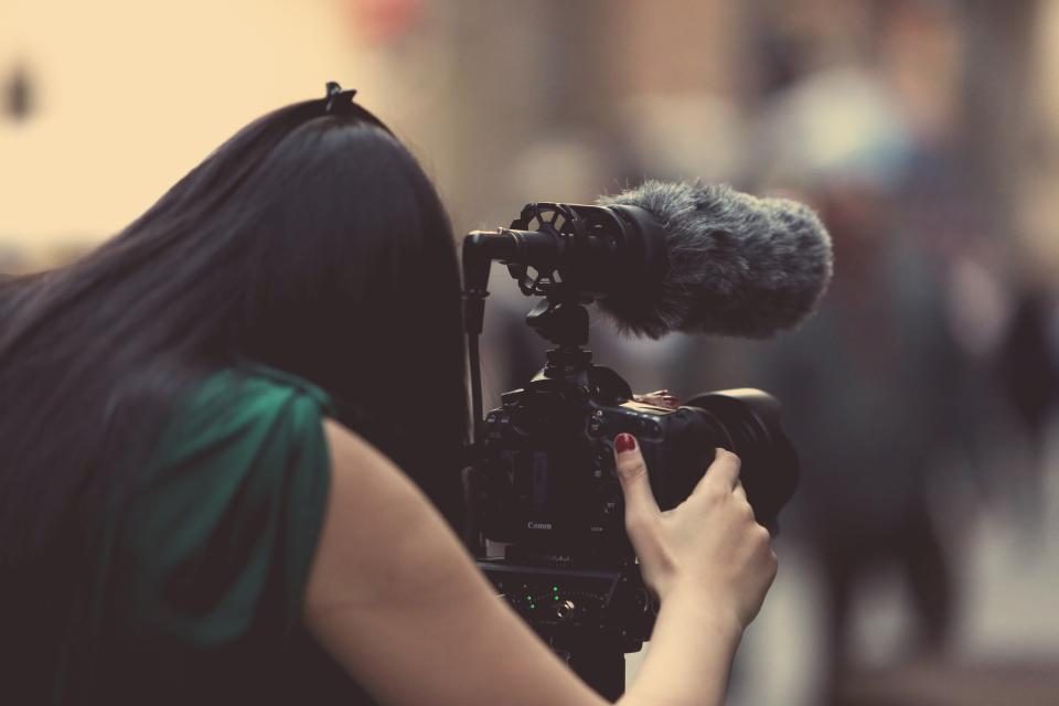 Mulher gravando um vídeo com uma câmera profissional e microfone