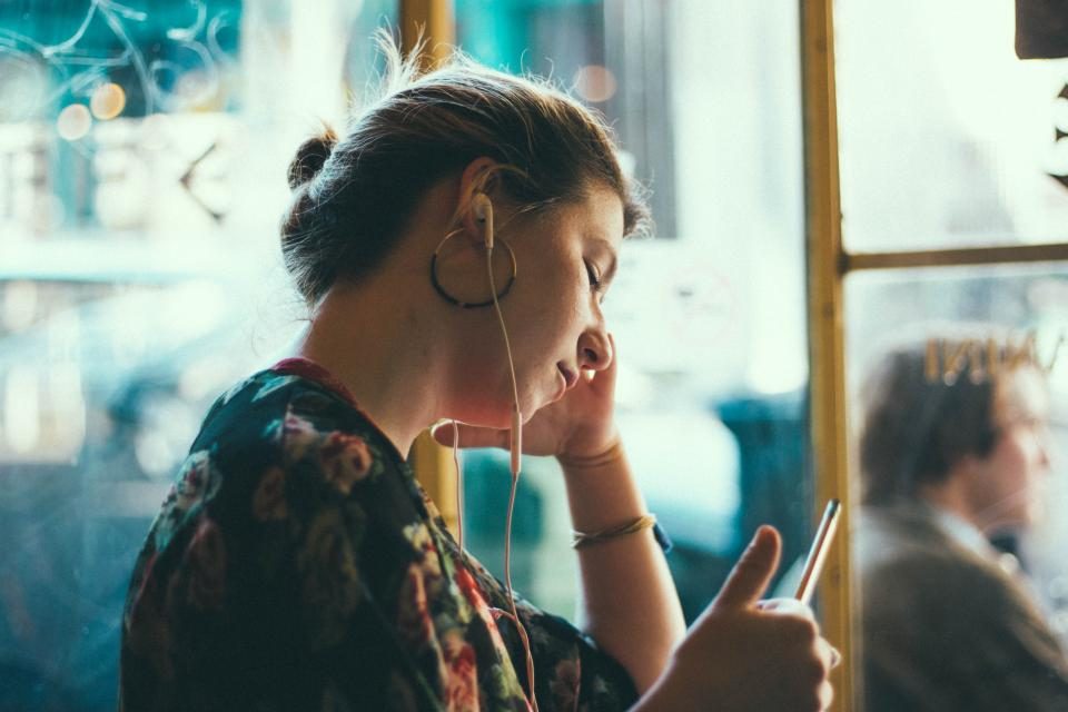 Mulher olhando para o celular com expressão impaciente
