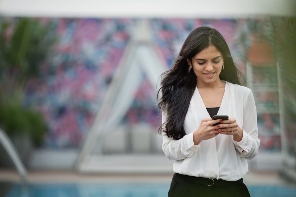 Mulher sorrindo enquanto troca mensagens no celular