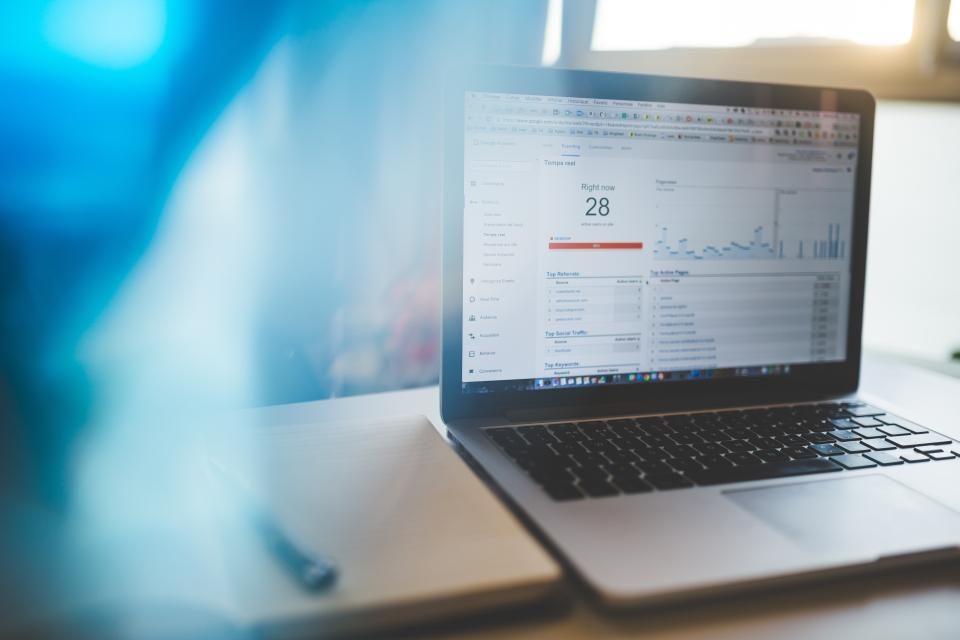 Notebook com um painel de métricas na tela em uma mesa iluminada