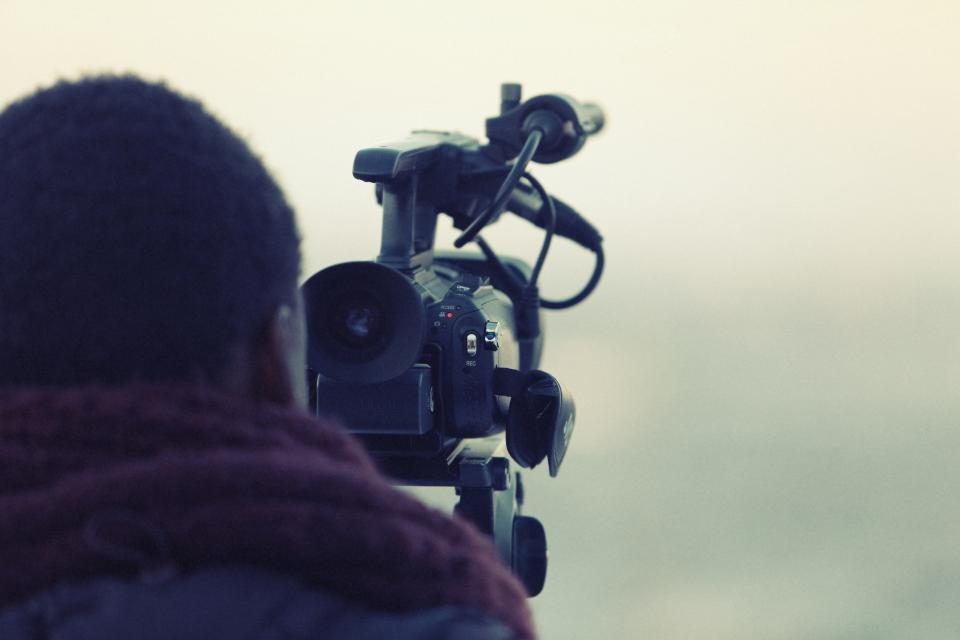 Pessoa filmando com uma câmera de vídeo, vista de trás