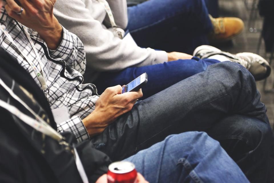 Pessoas sentadas lado a lado usando o celular durante um intervalo