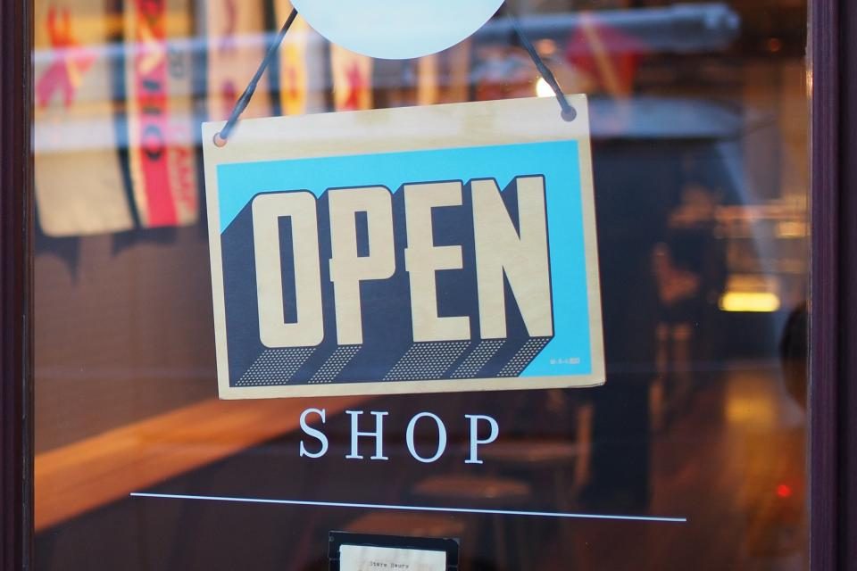 Placa de “Open Shop” pendurada na porta de vidro de uma loja