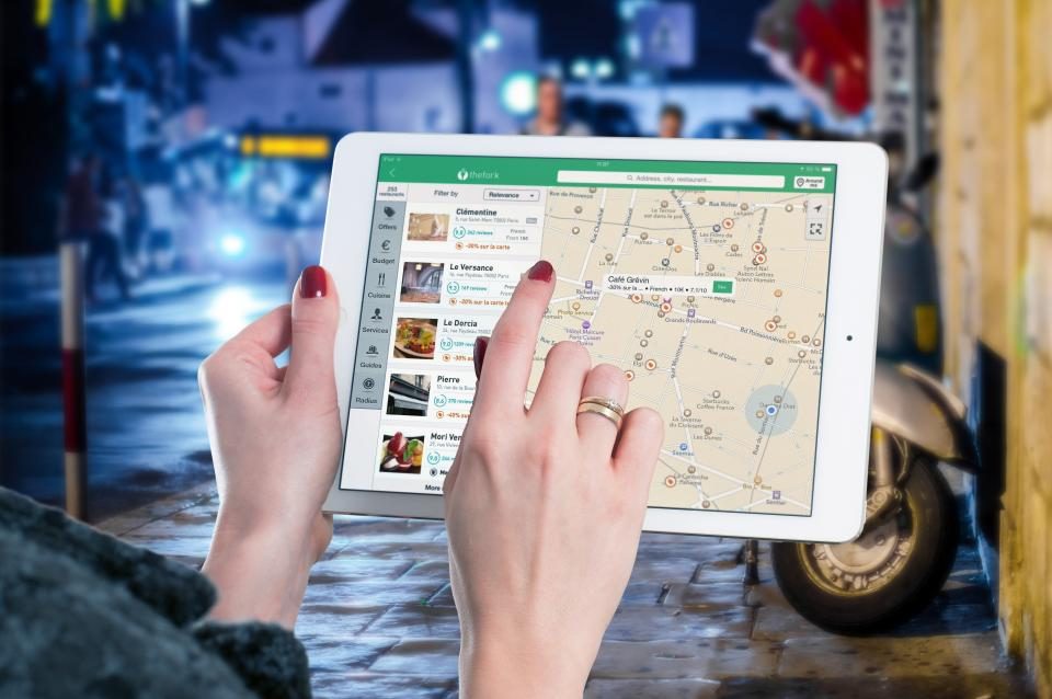 Mãos segurando um tablet com um mapa de navegação aberto na tela