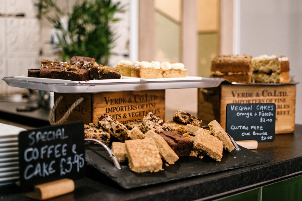 Vitrine de padaria com bolos, brownies e uma placa de café com bolo
